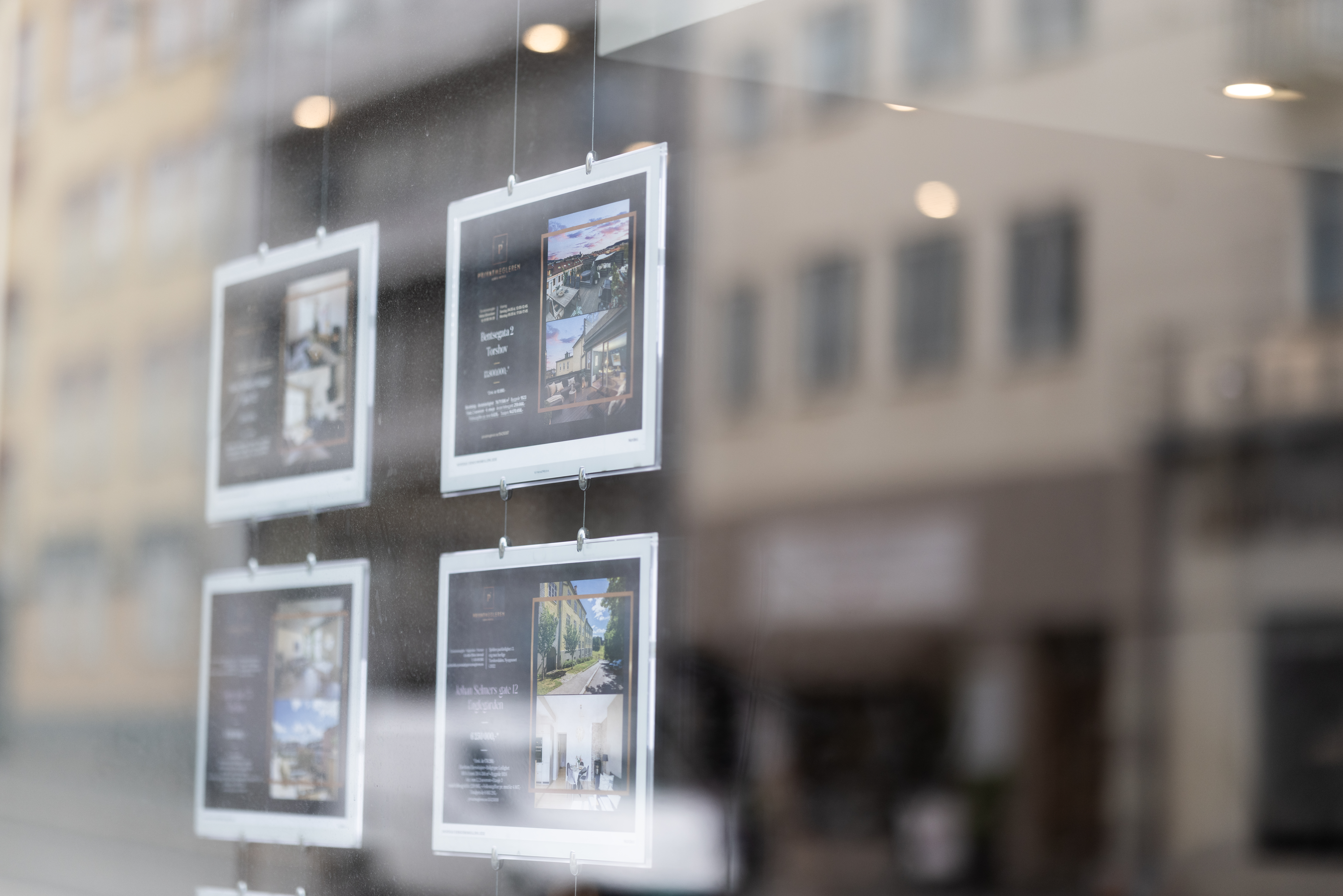 Boligannonser henger på wire i vinduet hos et meglerkontor, brukt som illustrasjon i artikkel om de beste eiendomsmeglerne på Fosen.