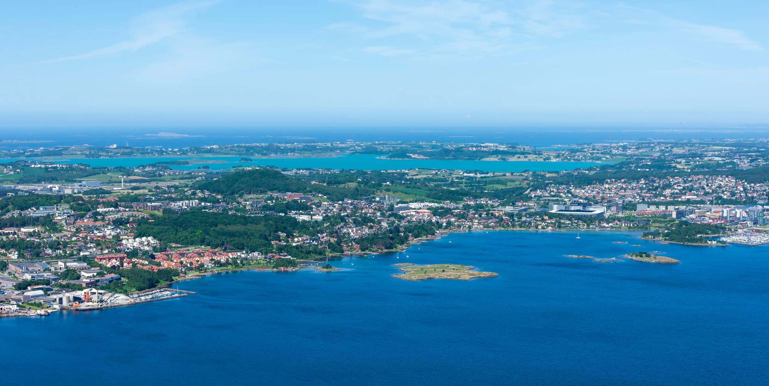 Panoramabilde av Sandnes sett fra luften med småbåthavn, villastrøk og Gandsfjorden i forgrunnen, brukt som illustrasjon i artikkel om hva eiendomsmegler koster i kommunen.