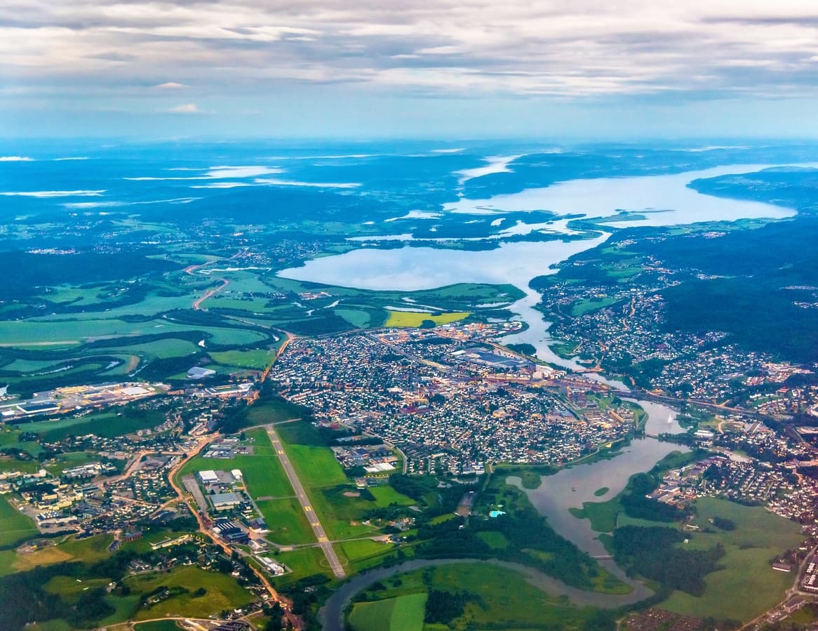 Flyfoto over Lillestrøm og Skedsmo med Kjeller flyplass, Nitelva og Øyeren, brukt i artikkel om eiendomsmegler i Skedsmo.