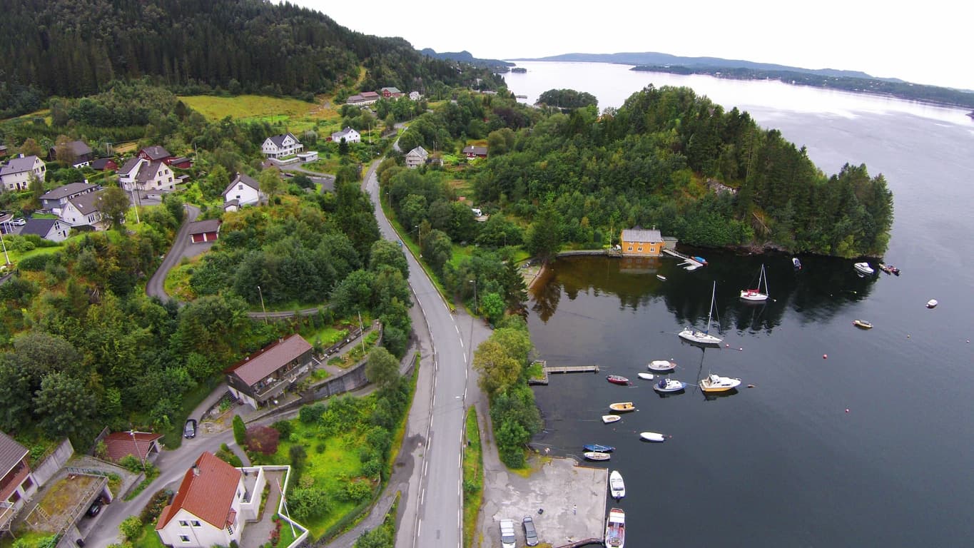Flyfoto over sjønært boligområde med småbåter ved kysten, brukt som illustrasjon i artikkel om eiendomsmegler i Bergen Sør.