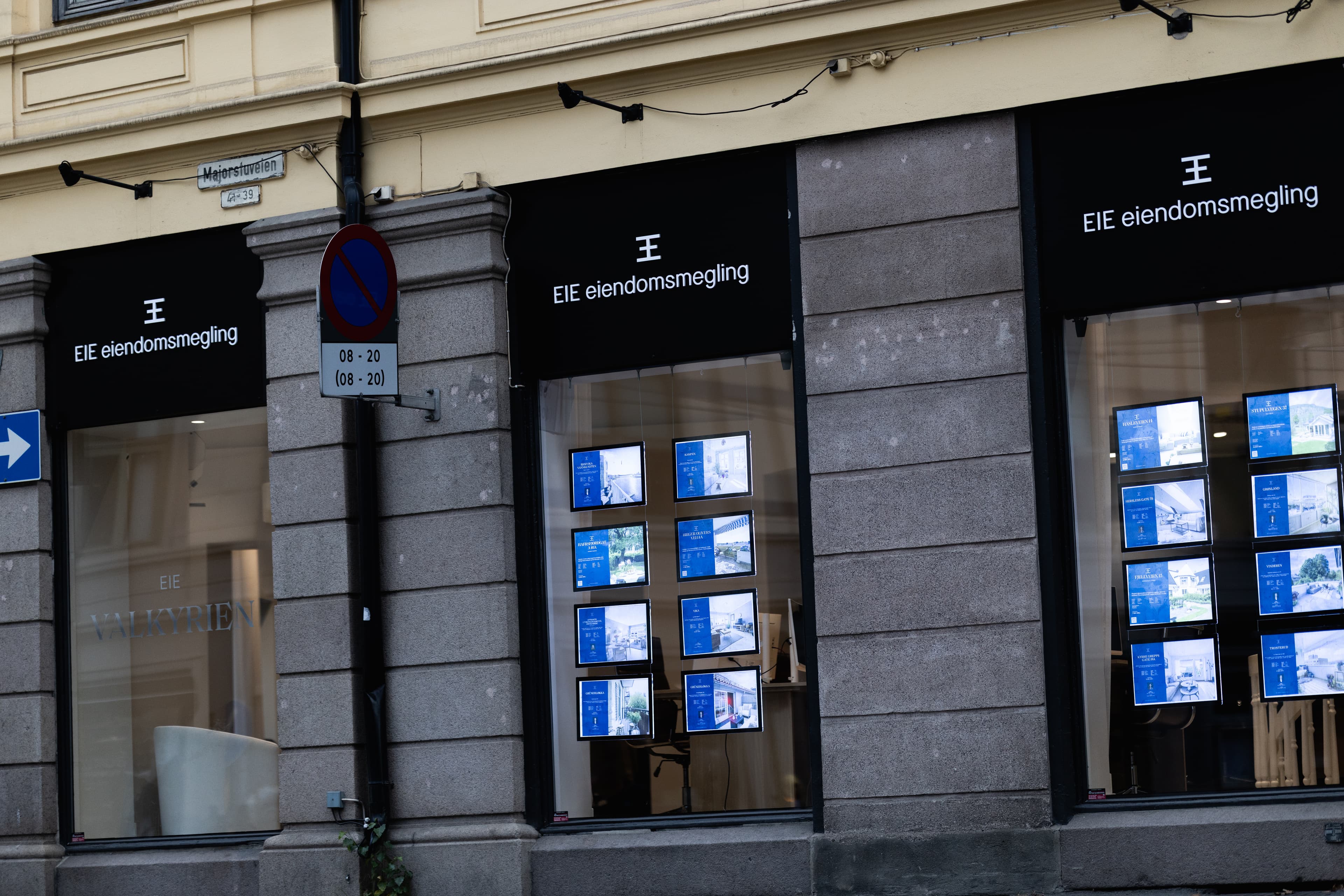 Meglerkontorets fasade med opplyste boligannonser i vindusutstillingen, brukt som illustrasjon i artikkel om eiendomsmegler på Bønes.