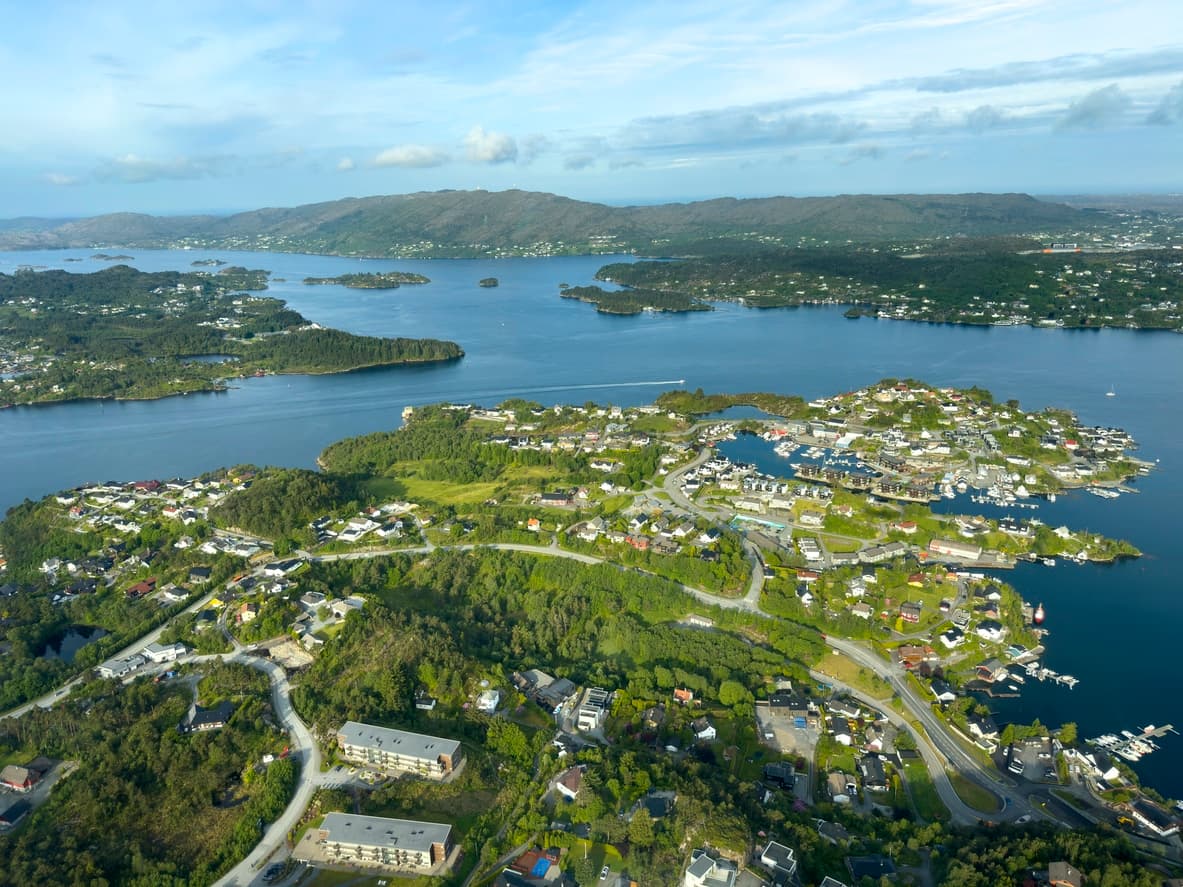 Luftfoto over boligområder med småbåthavn og fjordlandskap, brukt som illustrasjon i artikkel om eiendomsmegler på Sotra.