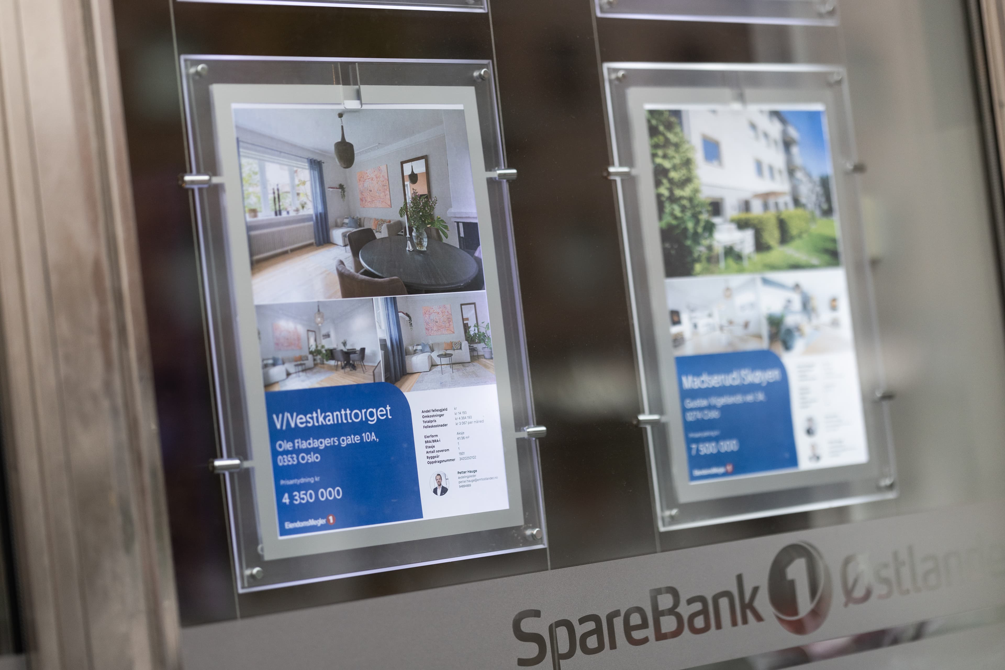 Opplyste boligannonser med interiørbilder og prisantydning i et meglervindu, brukt som illustrasjon i artikkel om eiendomsmegler på Byåsen.